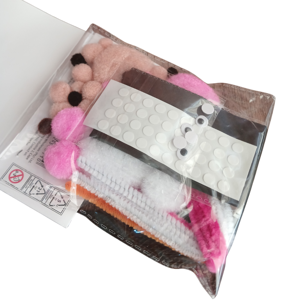 Close up view of craft supplies including pink and brown pom poms white pipe cleaners and googly eye stickers