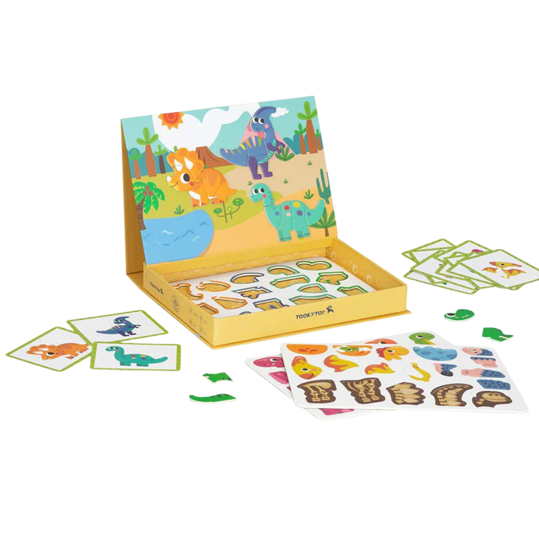 A child playing with the open TookyToy Magnetic Box, which shows a colorful dinosaur scene backdrop and magnetic puzzle pieces on a table.